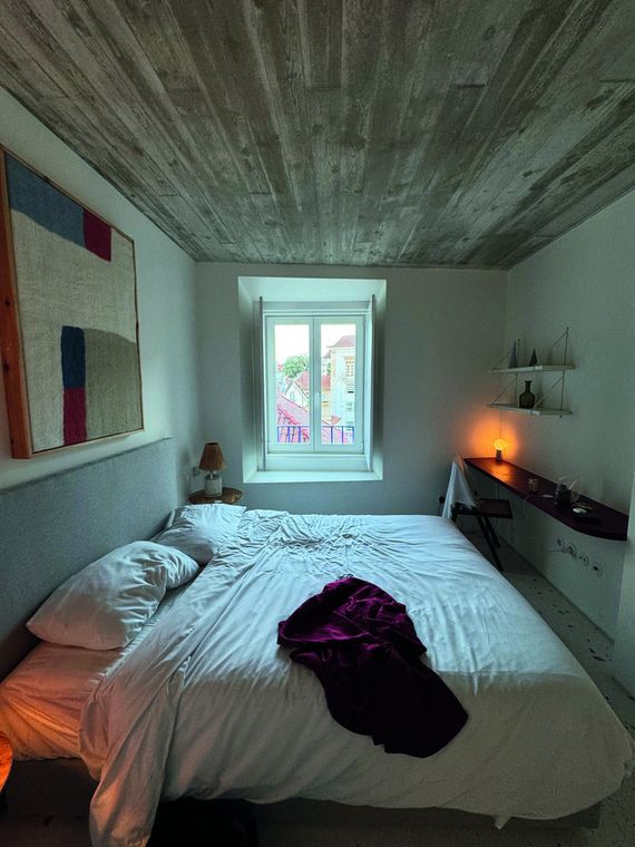 Habitación con techo de madera y una manta granate